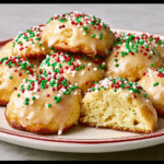 italian christmas desserts: A star-shaped Pandoro cake dusted with powdered sugar, set on a festive table with pine branches, golden lights, and red ornaments.